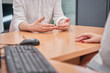 © Oscar - unrecognizable woman attending to a man in a clinic or at a reception desk. you can see the keyboard and mouse of the computer and the hands of a man and a woman talking.