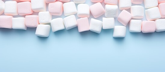 Fototapete - Marshmallows arranged in a flat lay composition with a copy space frame on a pastel pink and blue background Minimal yet creative concept