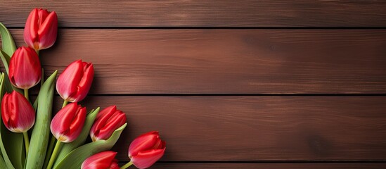 Sticker - A top down view of red tulips displayed on a rustic wooden table with ample empty space for other elements in the image