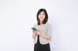 Asian woman is using a mobile phone against a white background.