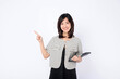 Asian woman is holding a tablet and pointing finger to an empty space against a white background.