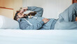 © peopleimages.com - Tired, sleep and man in bed with headache, stress and mental health burnout in home. Fatigue, insomnia and person with depression, anxiety or migraine in bedroom to relax, rest or thinking in morning