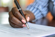 © Alexandra - Close-up of a  Afro-American person  signing a legal or business document, focus on hand and pen details