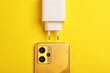Smartphone with charging adapter on yellow background