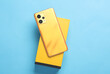 Yellow Modern new smartphone with box on blue background. Top view