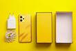 New smartphone with box and accessories on a yellow background. Yellow color trend. Modern gadgets, unboxing. Top view. Flat lay