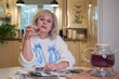 © Vieille Prune - a blonde woman in a blue jumper sitting at a table drinking tea