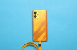 Yellow smartphone with a connected cable on blue background. Top view