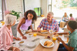 © Monkey Business - Grandparents With Teenage Grandchildren Indoors At Home Eating Breakfast With Parents In Background