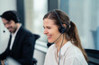 © KANGWANS - A woman wearing a headset is sitting at a desk in front of a computer monitor. She is focused on her work, possibly on a phone call
