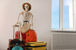 © New Africa - Waiting concept. Human skeleton in hat with suitcases indoors