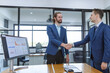 Successful businessmen handshaking after negotiation. Two smiling businessmen shaking hands while standing in an office. Business people shaking hands, finishing up a meeting