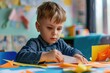 © Ева Поликарпова - Young boy sitting at a table cutting paper. Ideal for educational or creative projects