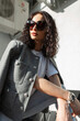 Cool fashion street curly beautiful girl model in fashionable casual clothes with sunglasses posing on the street