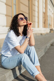 Fototapeta Panele - young beautiful girl with vintage sunglasses in a white T-shirt and jeans sits in the city on a summer day