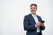 © Stock 4 You - Mature businessman in suit holding cellphone isolated, white background. Smiling Latin business man using smartphone mobile phone screen device, scrolling app, working and looking aside. Copy space