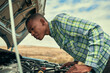 © peopleimages.com - Black man, engine and check car issue on road, hood and roadside assistance for auto service. Male person, battery and power issue with vehicle on street, cables and driver for transport emergency