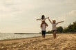 © sorapop - Road trips day. Happy family people having fun in summer vacation on beach, daughter riding on father back and mother running race at sand beach, enjoying road family trip playing together outdoor