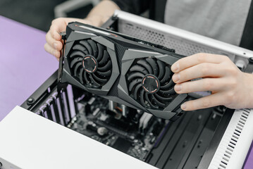 system administrator installing graphics card into system unit, assembling pc of different accessori