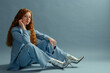 Fashionable redhead woman wearing elegant classic blue suit blazer, trousers, trendy silver ankle boots. Studio full-length  fashion portrait. Copy, empty, blank space for text