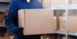 Banner center logistic and delivery. Worker in blue uniform hold cardboard box on background warehouse storage