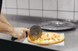 Pizzamaker worker cuts fresh pizza, business pizzeria concept