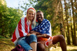 Happy American couple wrapped in national flag looking at camera.