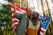 Happy patriotic couple with American flag in nature.
