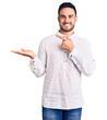© Krakenimages.com - Young handsome man wearing casual clothes amazed and smiling to the camera while presenting with hand and pointing with finger.