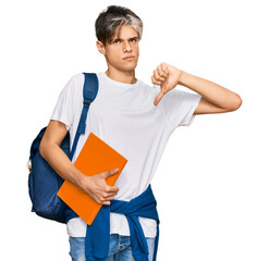 Canvas Print - Young hispanic man wearing student backpack and holding books with angry face, negative sign showing dislike with thumbs down, rejection concept