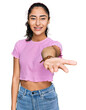 © Krakenimages.com - Hispanic teenager girl with dental braces wearing casual clothes smiling cheerful offering palm hand giving assistance and acceptance.