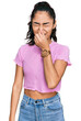 © Krakenimages.com - Hispanic teenager girl with dental braces wearing casual clothes smelling something stinky and disgusting, intolerable smell, holding breath with fingers on nose. bad smell