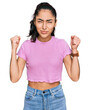 © Krakenimages.com - Hispanic teenager girl with dental braces wearing casual clothes angry and mad raising fists frustrated and furious while shouting with anger. rage and aggressive concept.