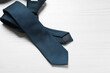 One blue necktie on white wooden table, top view. Space for text