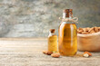 Almond oil in bottles and nuts on wooden table, closeup. Space for text