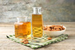 Almond oil in bottles and nuts on wooden table, closeup