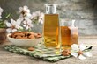 Almond oil in bottles, flowers and nuts on wooden table, closeup