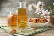 Almond oil in bottles, flowers and nuts on wooden table, closeup