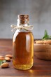 Almond oil in bottle, leaves and nuts on wooden table, closeup