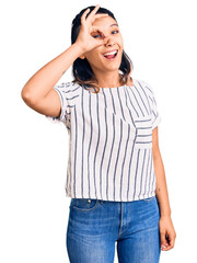 Canvas Print - Young woman wearing casual clothes doing ok gesture with hand smiling, eye looking through fingers with happy face.