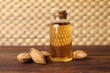 Almond oil in bottle and nuts on wooden table, closeup