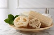 Loofah sponges, soap and green leaves on white marble table
