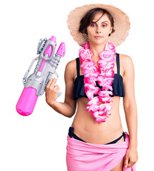 Poster - Beautiful young woman with short hair wearing bikini and hawaiian lei holding water gun thinking attitude and sober expression looking self confident