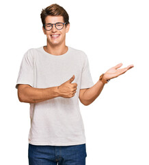 Wall Mural - Handsome caucasian man wearing casual clothes and glasses showing palm hand and doing ok gesture with thumbs up, smiling happy and cheerful