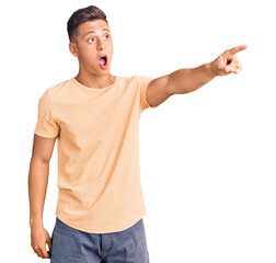 Canvas Print - Young handsome man wearing casual clothes pointing with finger surprised ahead, open mouth amazed expression, something on the front