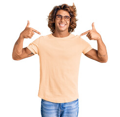 Wall Mural - Young hispanic man wearing casual clothes and glasses looking confident with smile on face, pointing oneself with fingers proud and happy.