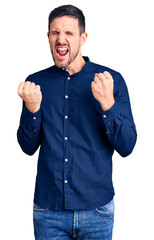 Wall Mural - Young handsome man wearing casual shirt celebrating surprised and amazed for success with arms raised and eyes closed. winner concept.