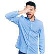 © Krakenimages.com - Hispanic man with beard wearing casual business shirt peeking in shock covering face and eyes with hand, looking through fingers with embarrassed expression.