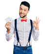 © Krakenimages.com - Hispanic man with beard holding poker cards doing ok sign with fingers, smiling friendly gesturing excellent symbol