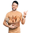 © Krakenimages.com - Hispanic man with beard holding wicker basket with bread smiling happy pointing with hand and finger to the side
